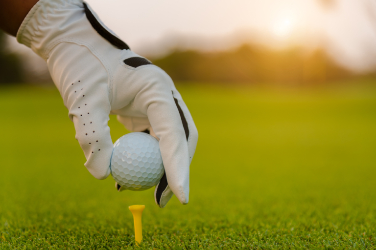 Photo of gloved hand placing golf ball on tee