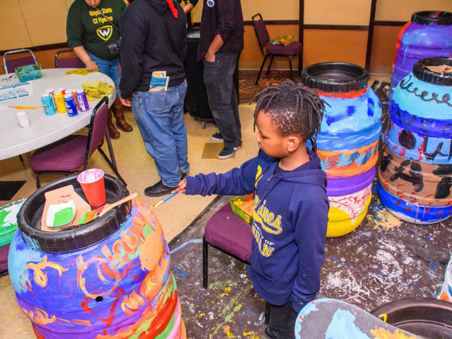 Child painting water barrel