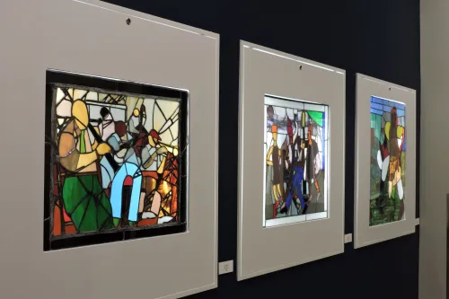 Several stained glass pieces, the first depicting a couple of musicians performing closely together.